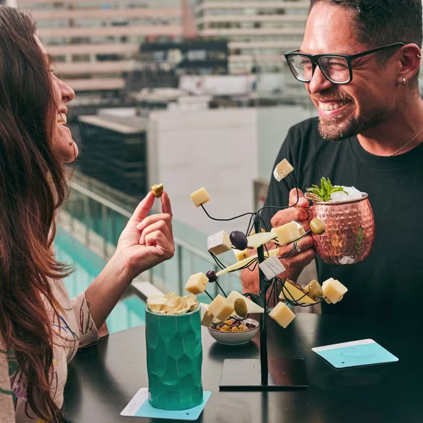 Una joven pareja disfruta del original plato "árbol de queso" y de unos exóticos cócteles con vistas a la ciudad de Lima en el bar Celeste.