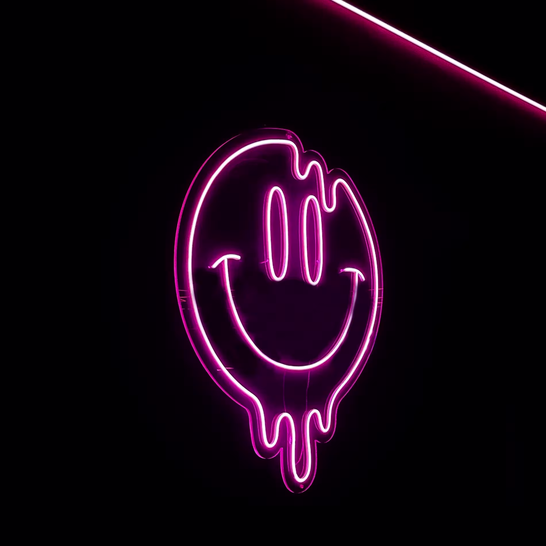Mobsters: Letrero de neón rosa con cara sonriente derretida sobre fondo negro, creando un ambiente moderno y vibrante.