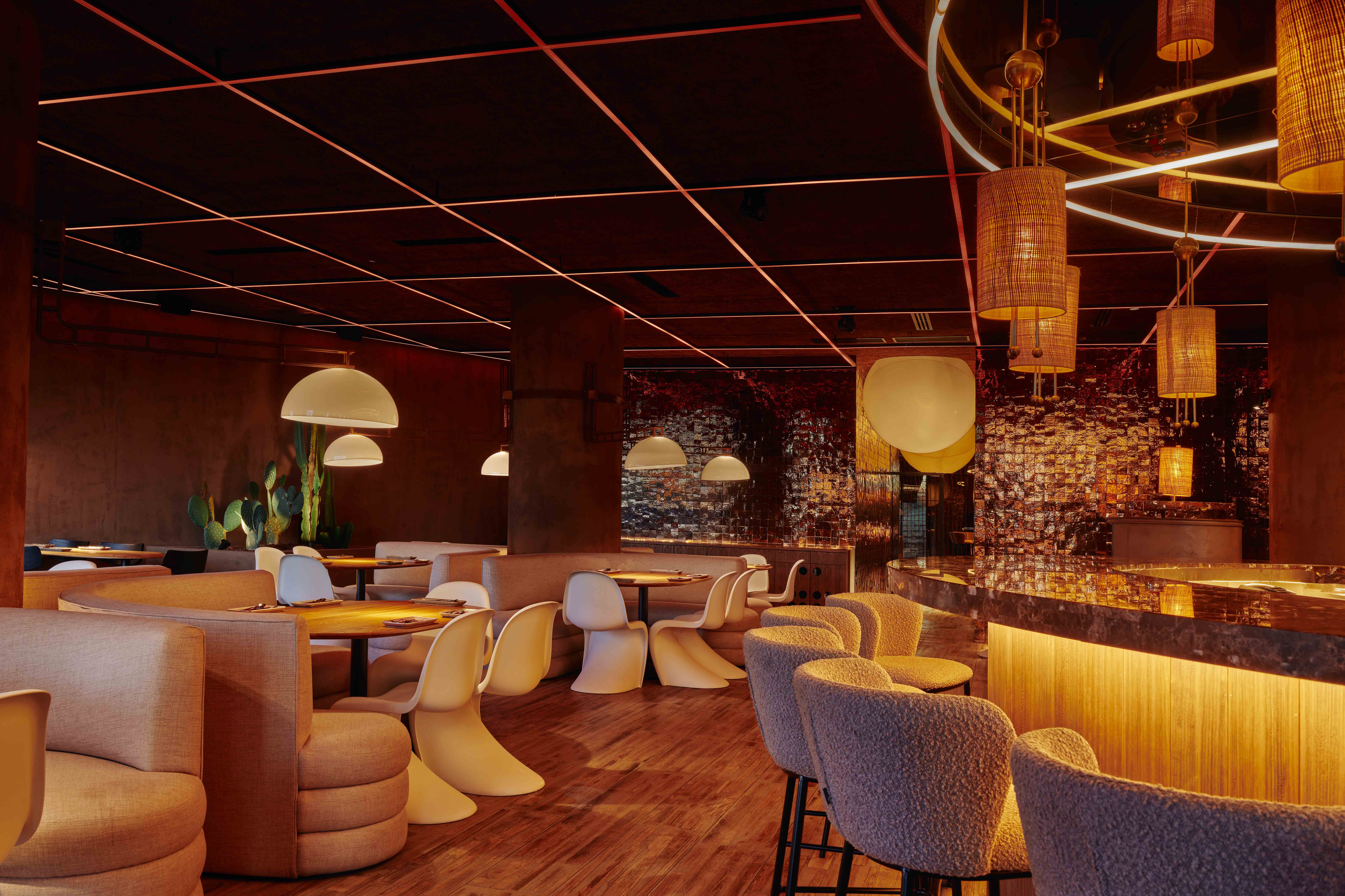 Interior de Ochenta Grados Valdebebas con iluminación cálida, mobiliario curvo, acabados en cobre brillante y un ambiente elegante y envolvente.