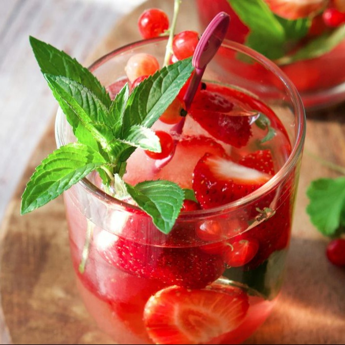 A strawberry mojito cocktail with a mint sprig garnish.