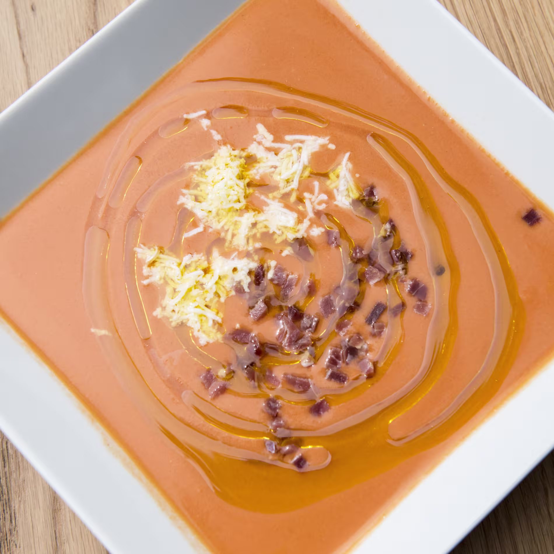 Un exquisito plato de salmorejo en Bienmesabe Príncipe de Vergara, adornado con huevo rallado, jamón picado y un chorrito de aceite de oliva.