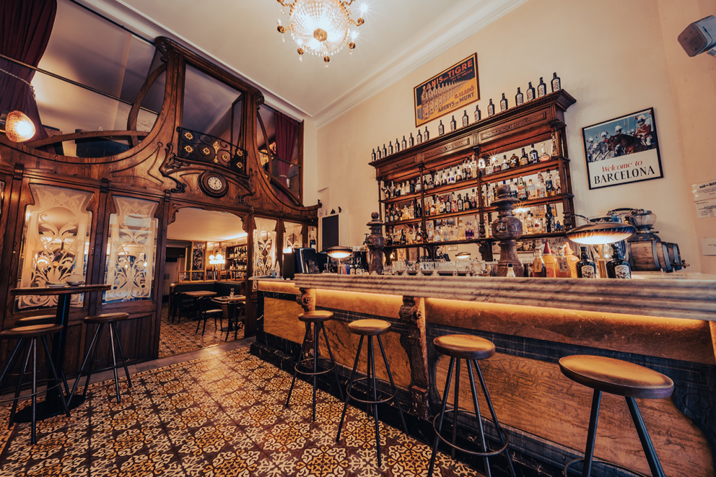 Bar Muy Buenas, un icónico bar modernista con detalles de época, barra de mármol y un ambiente acogedor que revive la esencia del Raval.