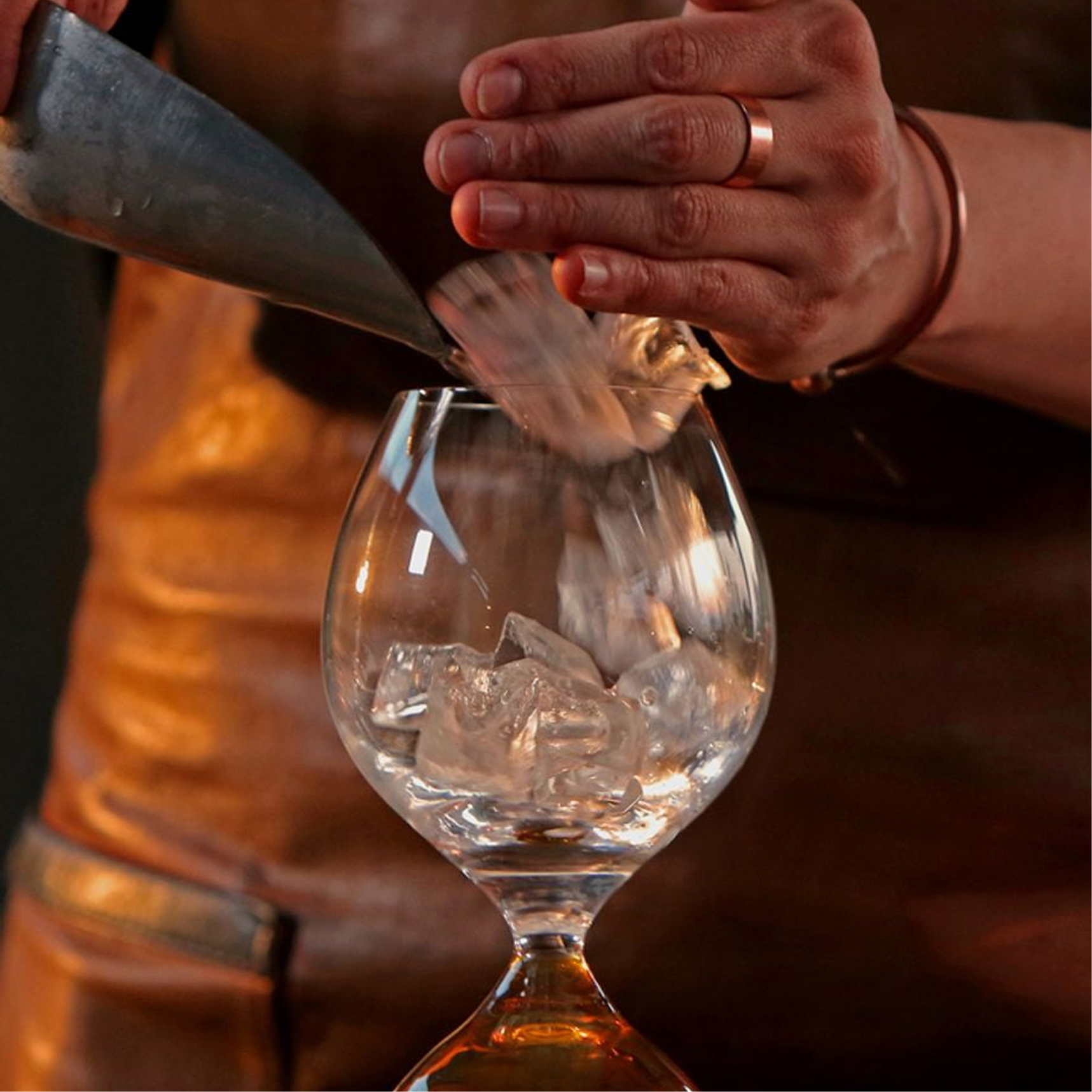 Ice being poured into a tulip-shaped whisky glass