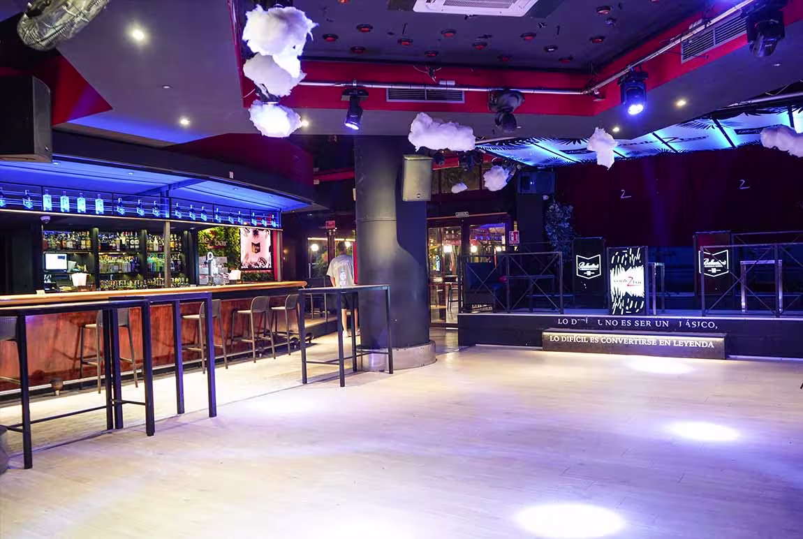 Voulezbar destaca con su barra iluminada, mesas altas de madera, techos decorados con nubes y un escenario que invita a disfrutar cada noche.
