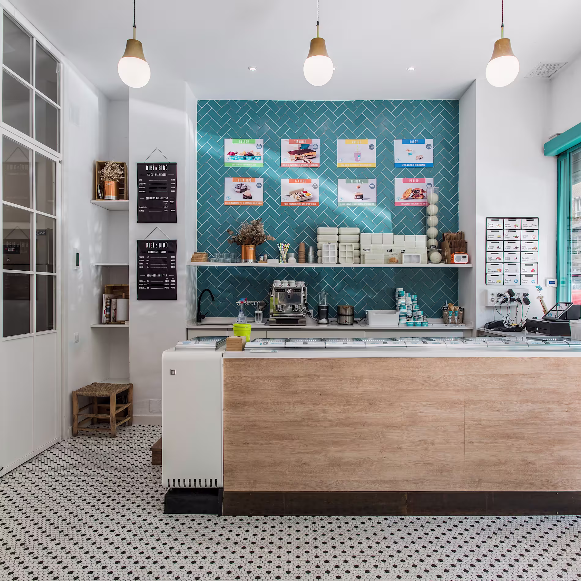 Interior del local con vitrina de helados, decoración en tonos madera y turquesa y carta expuesta sobre un azulejado geométrico.