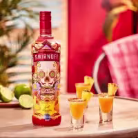 La imagen muestra una botella de Smirnoff Spicy Tamarind y tres vasos de shot.