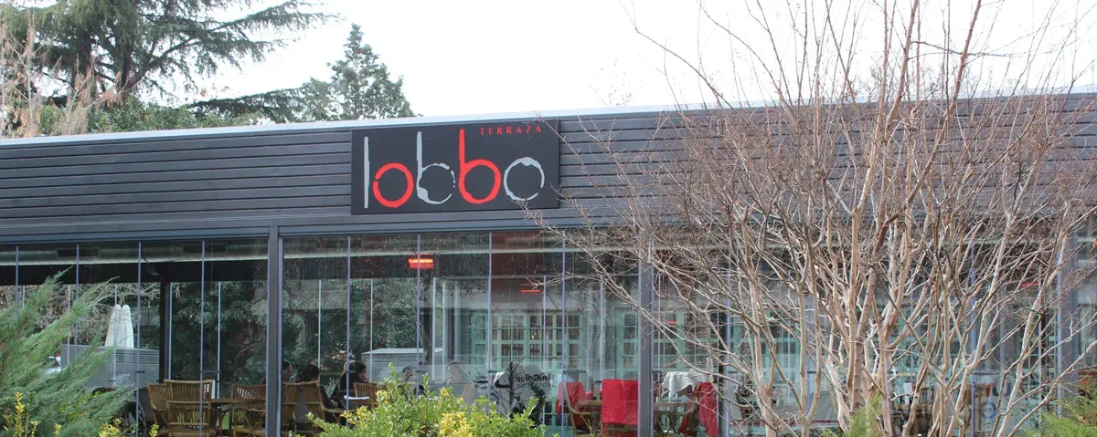 La fachada de Terraza Lobbo destaca por su diseño moderno, rodeado de jardines que invitan a disfrutar de una experiencia única en plena naturaleza.