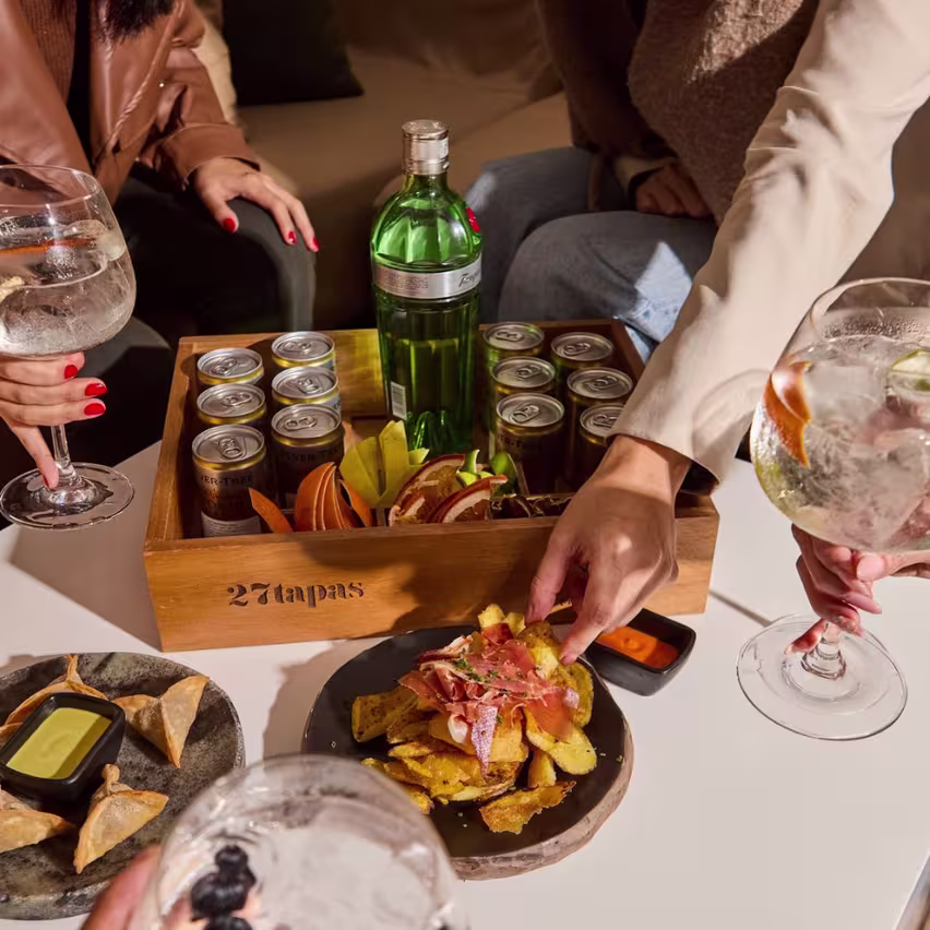 La imagen muestra una mesa en 27 tapas con cócteles y piqueos