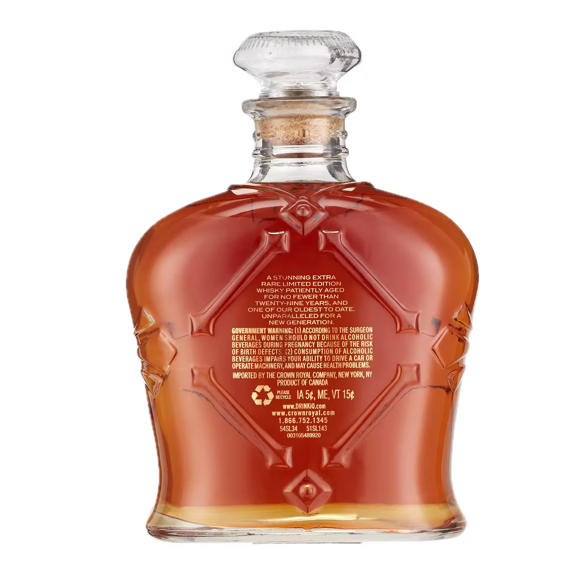 A full glass bottle of amber liquor with an ornate design, viewed from the back, showing a government warning and product information in gold text.