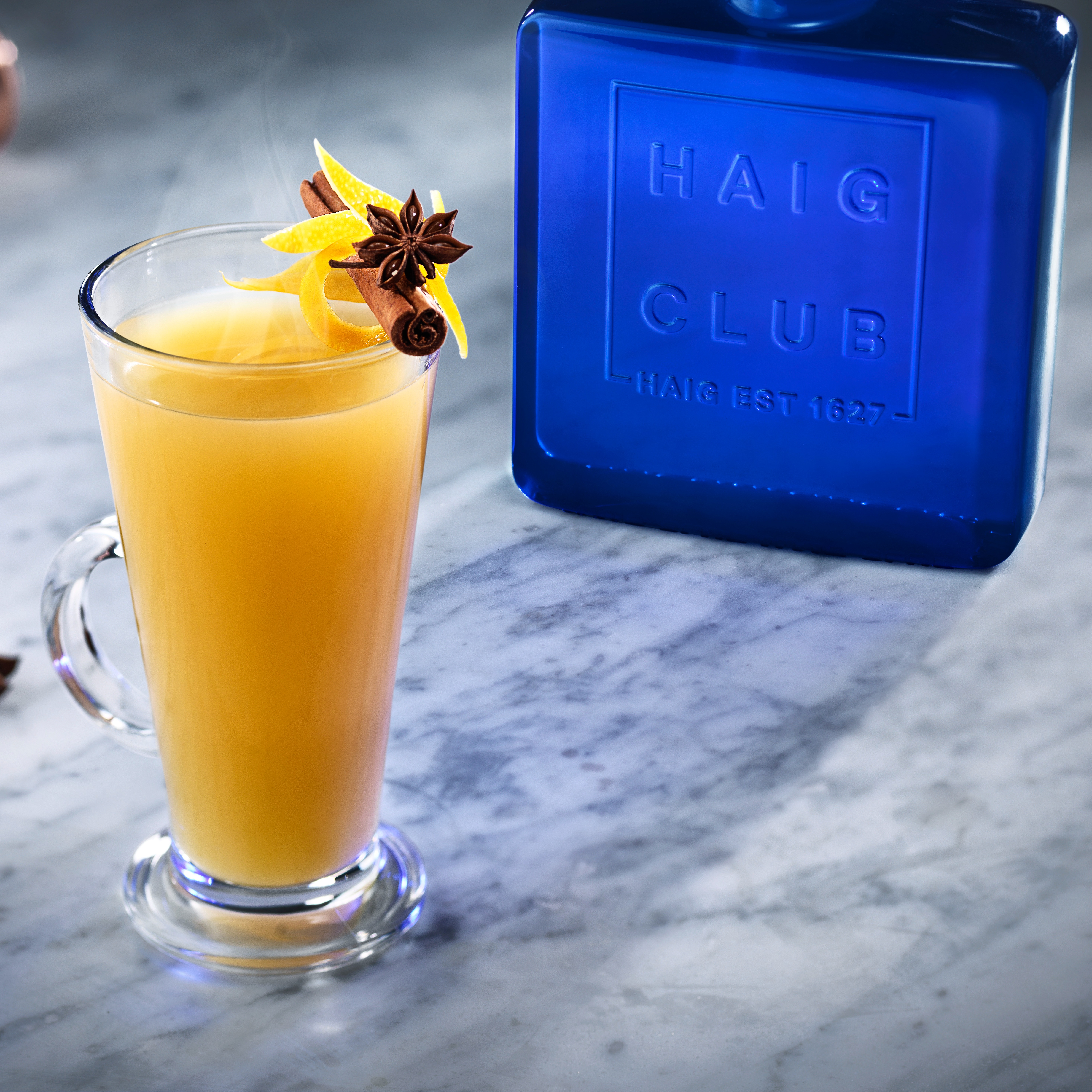 A Hot Toddy in a latte glass, next to a bottle of Haig Club whisky