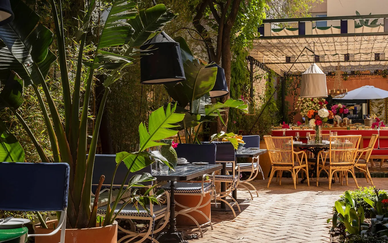 Terraza luminosa y tropical con vegetación exuberante, mesas elegantes y flores frescas. Ideal para un almuerzo al aire libre en un entorno encantador.