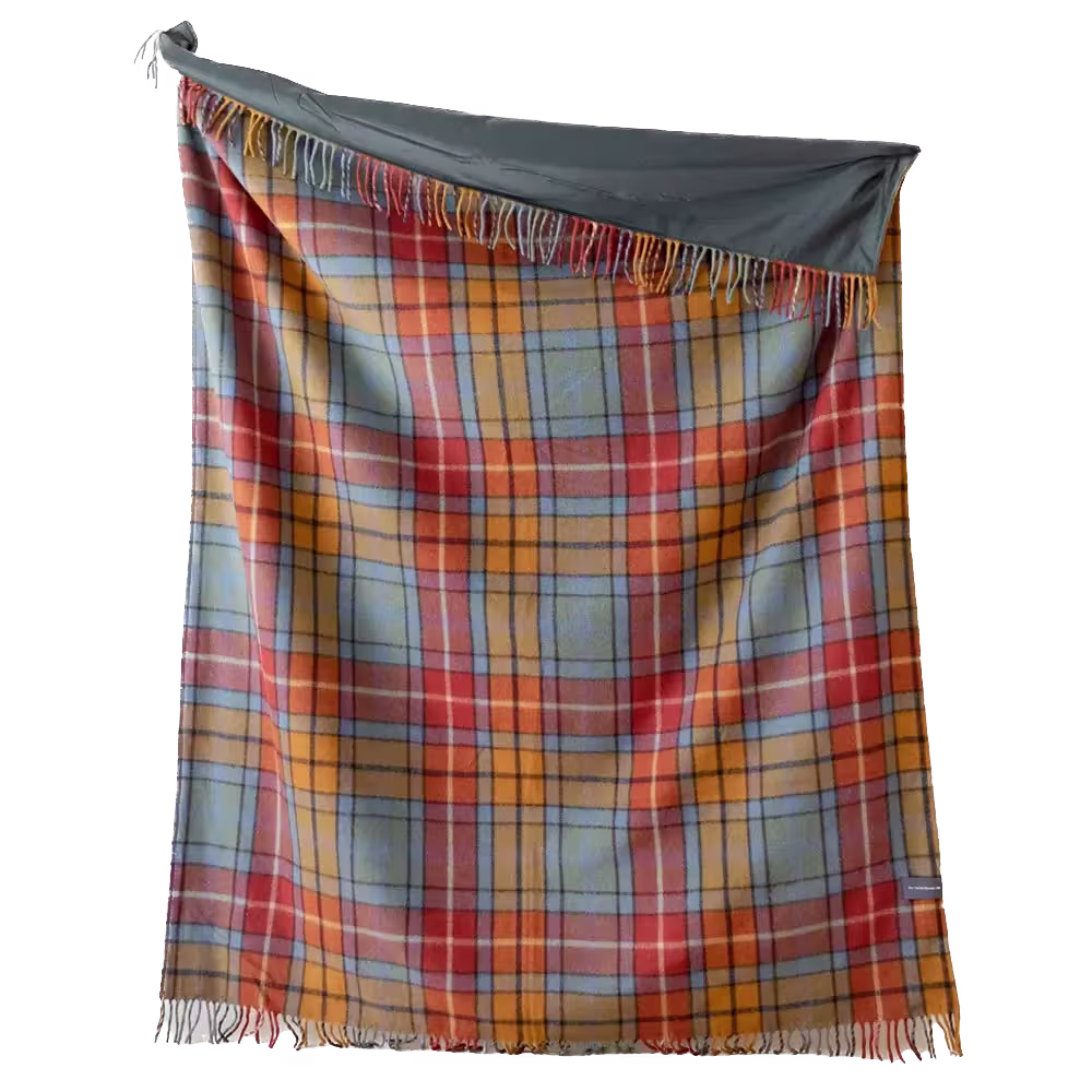 A multicolored plaid blanket with fringe is draped unevenly, exposing a gray fabric corner at the top left.