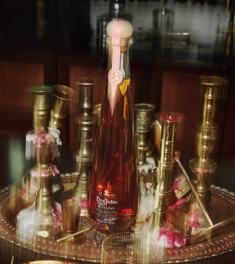 Don Julio Rosado next to cocktail and person's hand