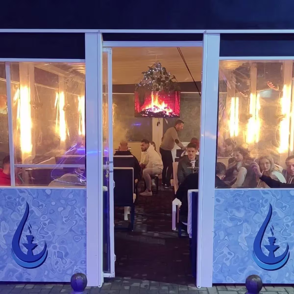 AQUA COCKTAILS BAR muestra una terraza iluminada con decoración minimalista, mesas llenas y un ambiente acogedor ideal para compartir.