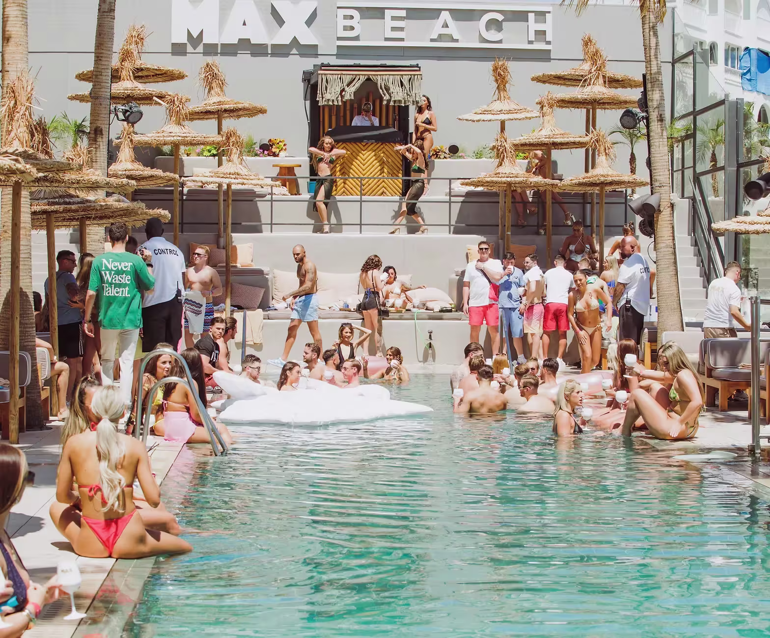 Max Beach destaca con su piscina infinita frente al mar, rodeada de cómodos sofás y sombrillas modernas, creando un ambiente relajado y elegante.