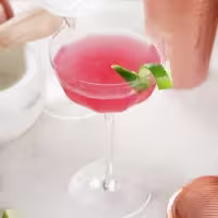 La imagen muestra una botella de vodka Smirnoff Green Apple y dos vasos rellenos con el cóctel Mojito con Vodka Smirnoff Green Apple.