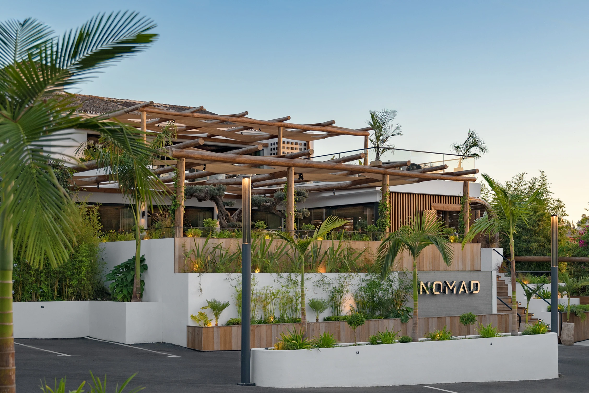 Nomad Restaurant & Lounge, exterior del restaurante rodeado de vegetación, ofreciendo un ambiente relajante con un diseño elegante y moderno.