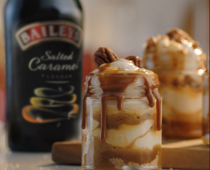 Detalle de postre hecho con Baileys. Botella de fondo difuminada.