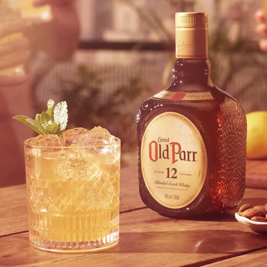 La imagen muestra un vaso relleno con el cóctel Old Parr Splash junto a una botella del whisky Old Parr 12 años.