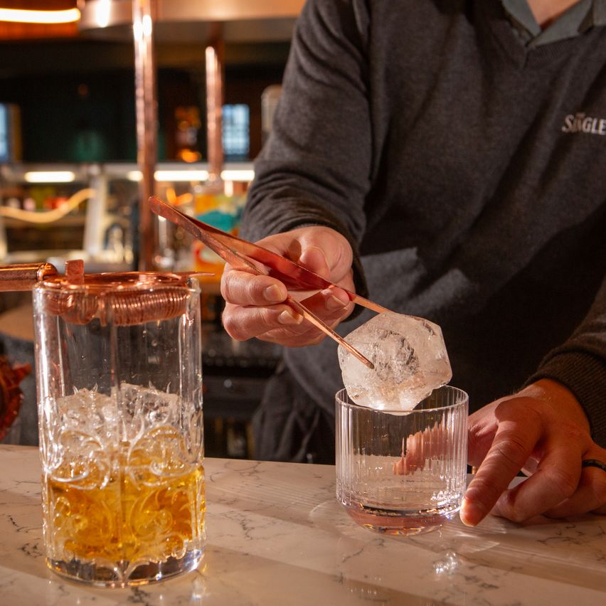 El bartender sirve un whisky en las rocas.