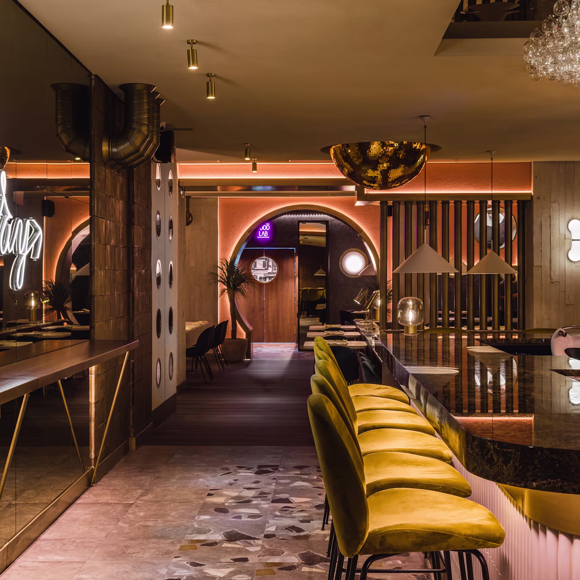 Interior sofisticado de 80 Grados Castellana, con barra de mármol, sillas doradas y una iluminación envolvente que crea un ambiente moderno y elegante.