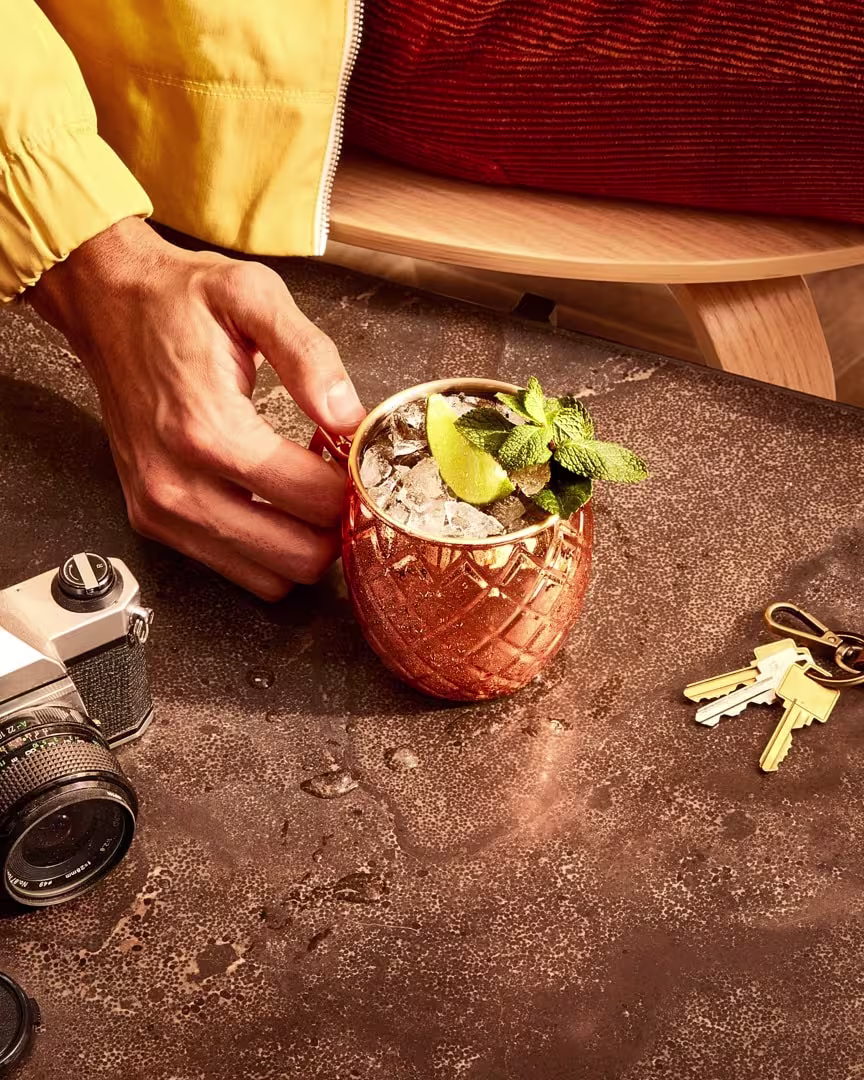 A moscow mule in a copper cup on a wooden table.