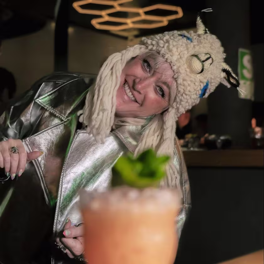 En la imagen se ve una mujer sonriendo y feliz, por delante uno de los cocteles preparados en el evento.