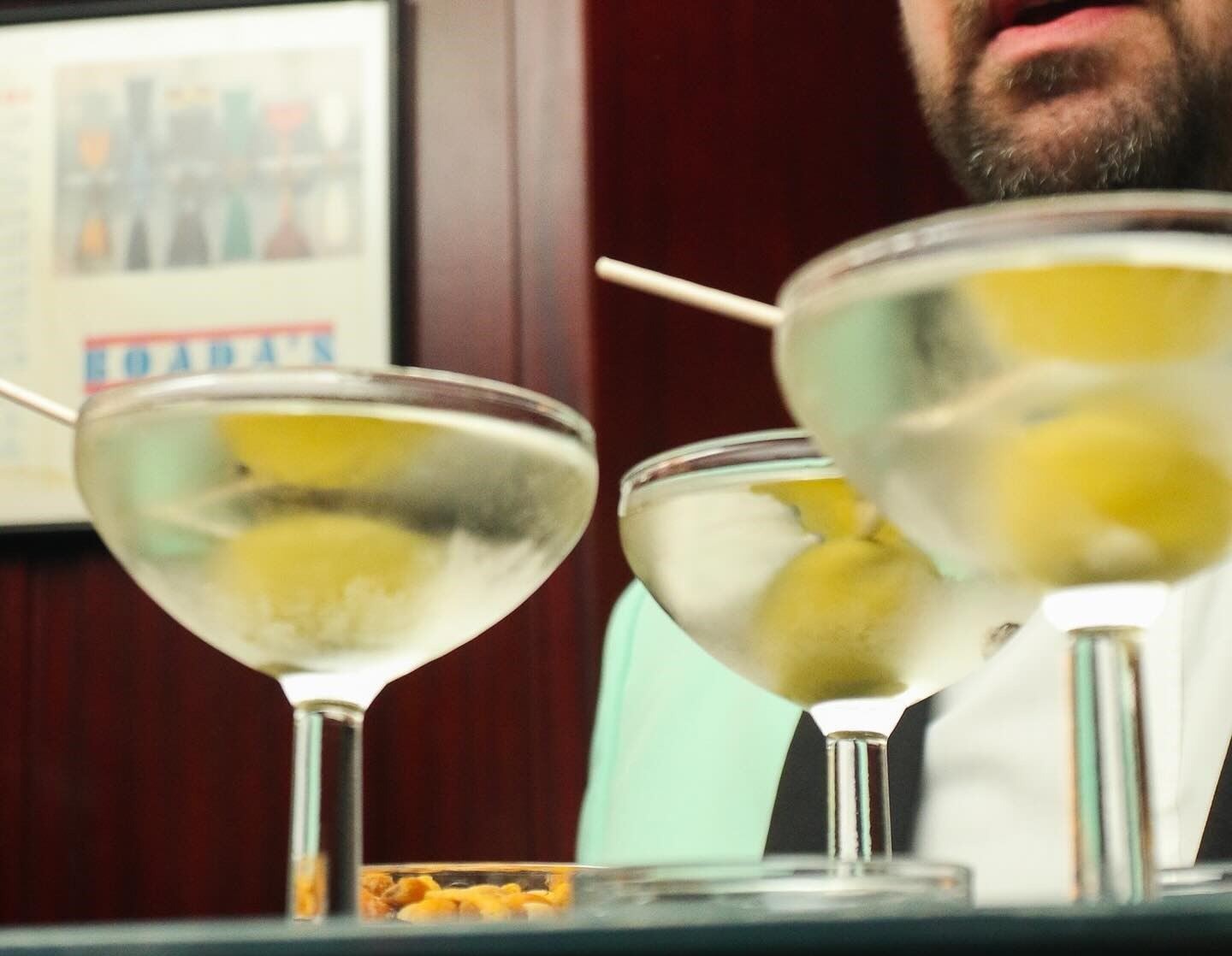 En Boadas, un camarero impecablemente vestido sirve martinis clásicos con aceitunas en un ambiente sofisticado y elegante.
