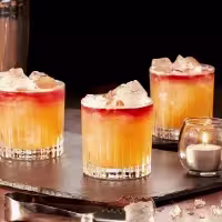 La imagen muestra tres vasos rellenos con el cóctel New York Sour.