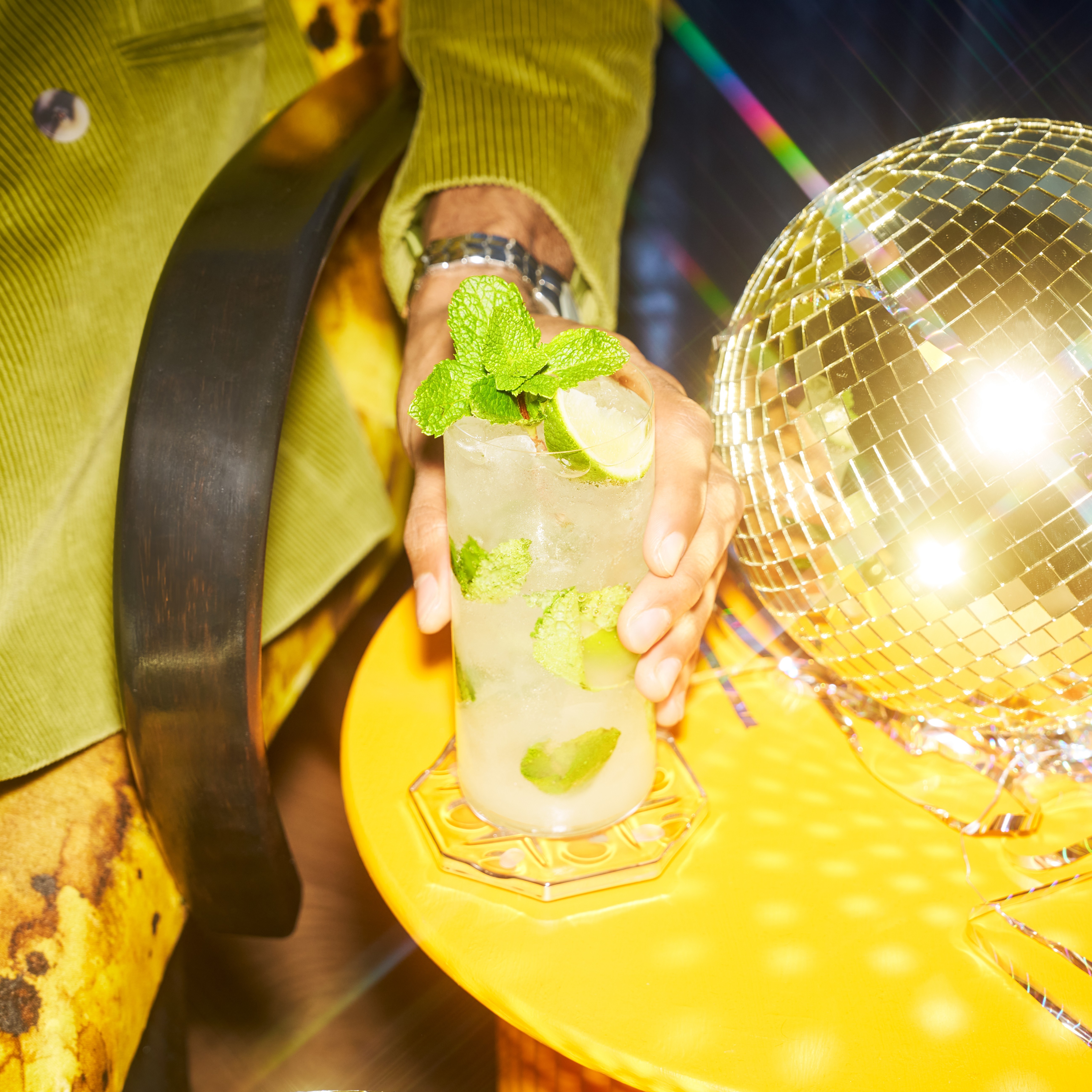 A mojito cocktail next to a disco ball.