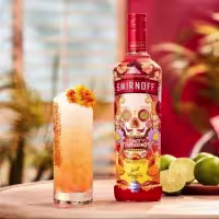 La imagen muestra una botella de Smirnoff Spicy Tamarind junto a una vaso relleno con un cóctel preparado con dicho destilado.