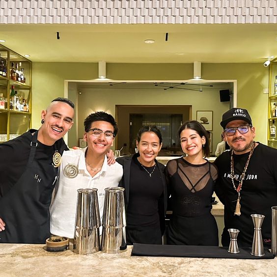 La imagen muestra a un grupo de personas detrás de la barra de un bar.