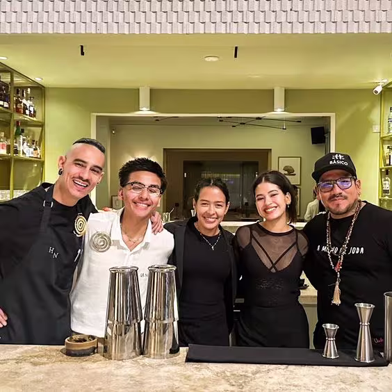 La imagen muestra a un grupo de personas detrás de la barra de un bar.