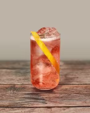 A fizzy pink cocktail with a lemon peel twist