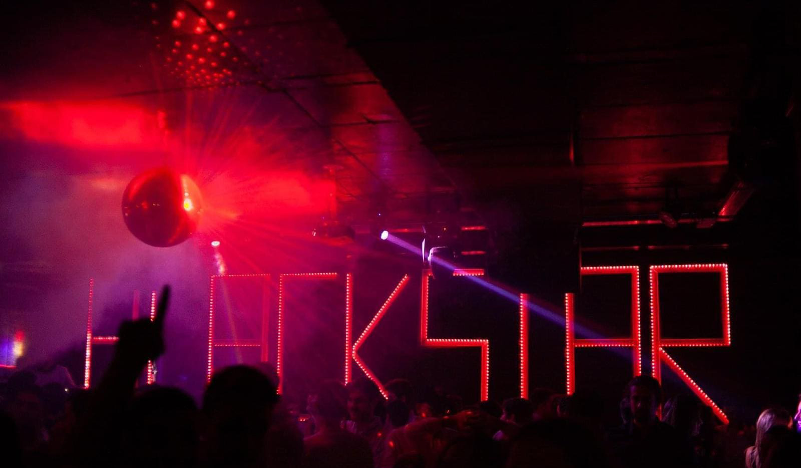 Ambiente vibrante en la discoteca Blackstar con iluminación roja, bola de espejos y letras decorativas iluminadas