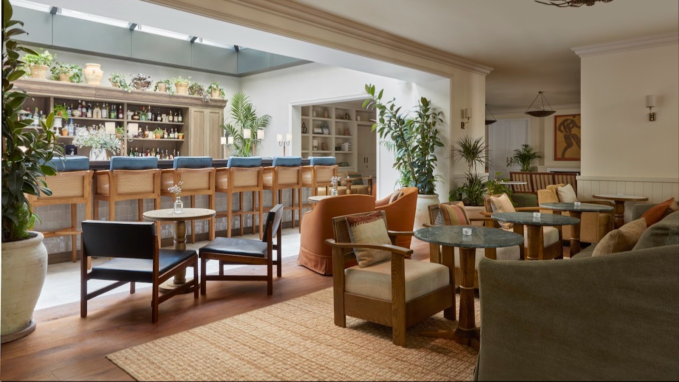 Espacio luminoso y acogedor con barra de cócteles, techos altos, plantas naturales y sillones tapizados que invitan a la calma y a la conversación.