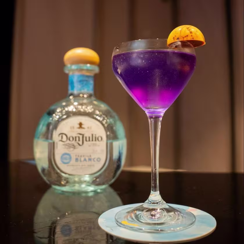 La imagen muestra una botella de tequila Don Julio Blanco junto a un vaso con un cóctel llamado “La Heredera” creado por el bartender finalista de World Class 2024 Perú, Carolin Ruiz de Astrid & Gastón.