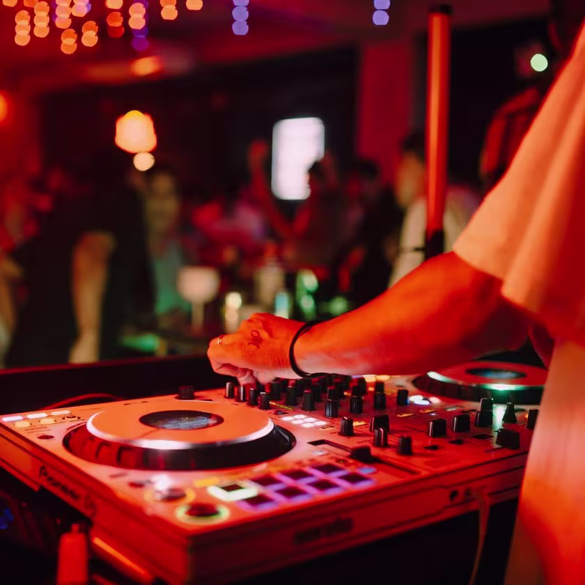 las manos de un DJ sobre una consola de música en una fiesta.