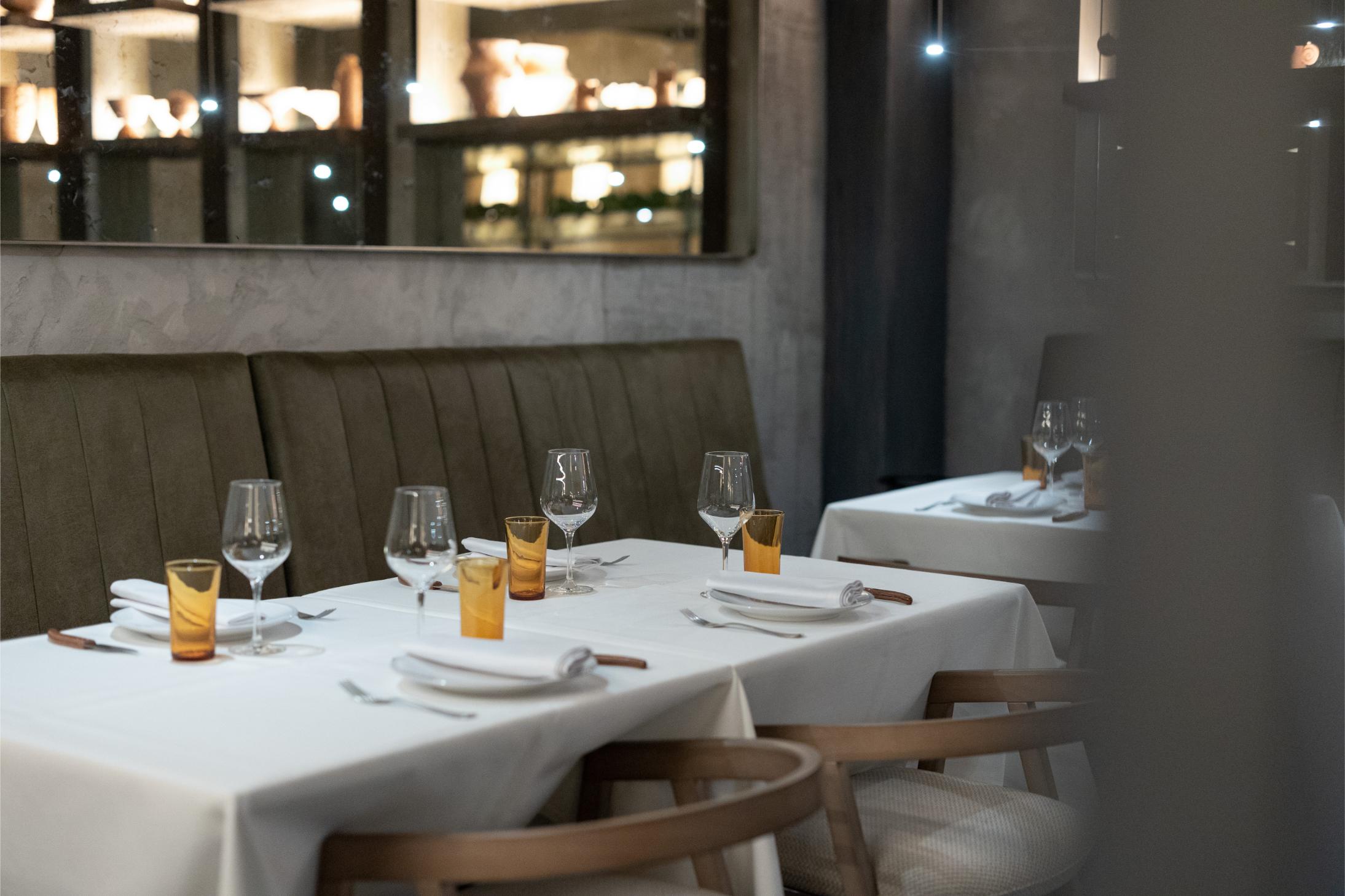 Interior de El Huerto de Floren Domezain con mesas elegantes, manteles blancos, copas y una decoración sofisticada en tonos cálidos y modernos.