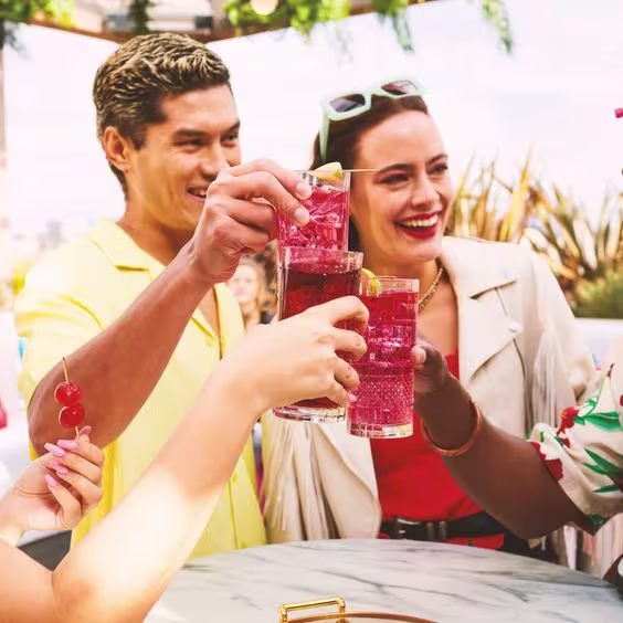 La imagen muestra cuatro personas brindando con vasos que contienen cócteles preparados con vodka Smirnoff.
