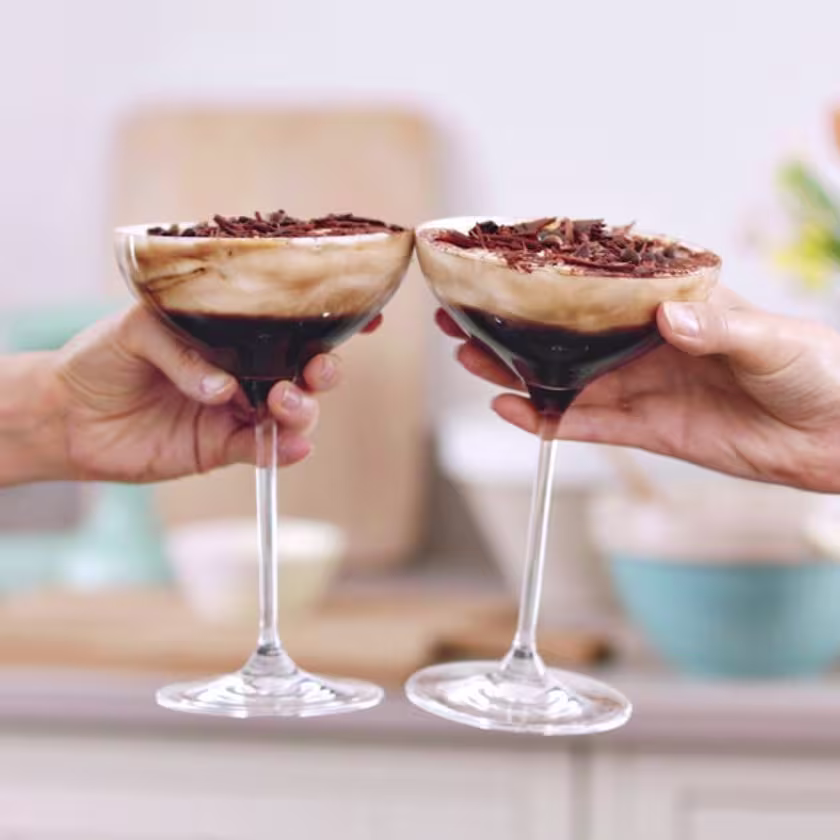 La imagen muestra dos copas brindando con cócteles preparados con Baileys.