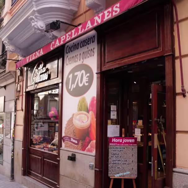 Fachada tradicional de Viena Capellanes Martín de los Heros con toldo burdeos y cartel de cocina casera. Un rincón clásico con esencia de barrio.
