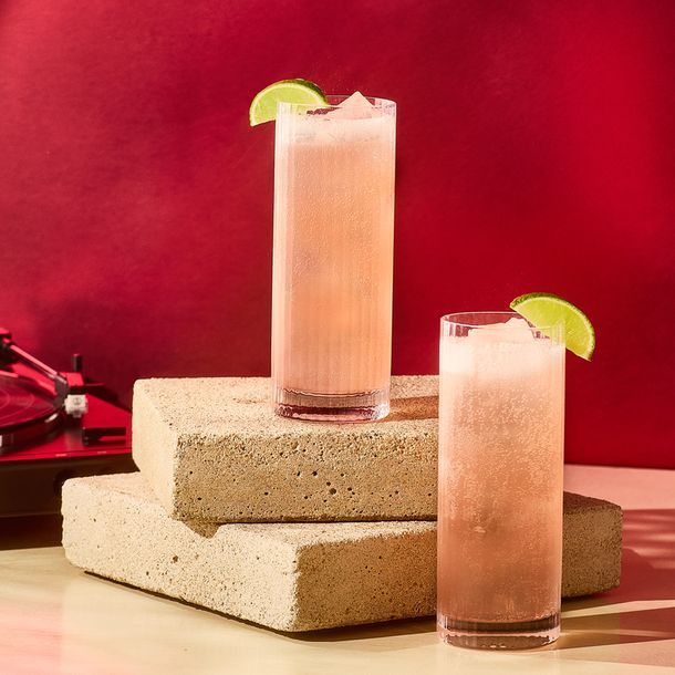 2 Paloma cocktails placed on a slab of rock with a red background 