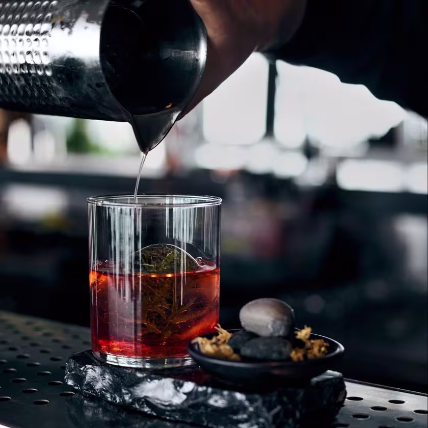 En la imagen se ve a un bartender preparando el coctel negroni en la barra del restobar Cala.