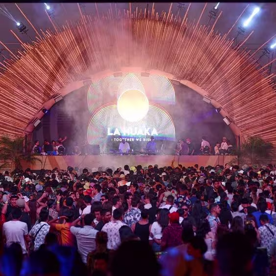 La imagen muestra un grupo de gente mirando hacia el escenario de La Huaka.