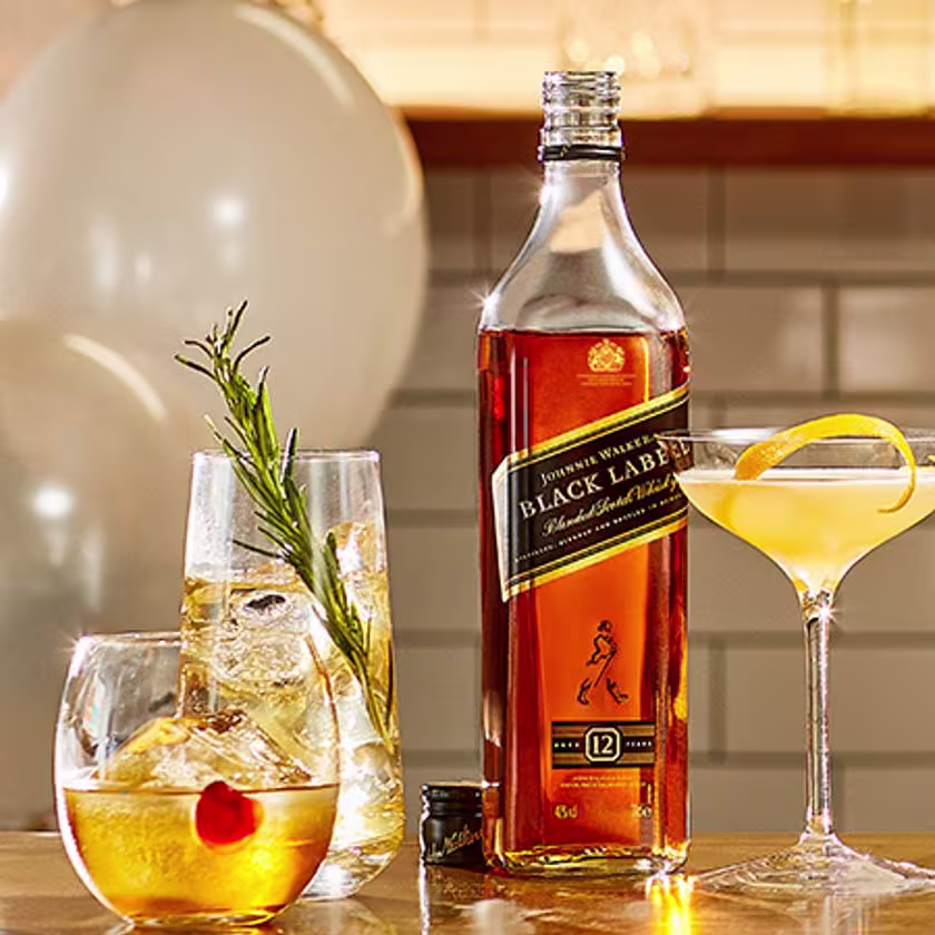La imagen destaca ingredientes salados y dulces, acompañados de una botella de whisky Johnnie Walker Black Label y tres cócteles distintos servidos en vasos diversos, todos elaborados con dicho whisky.
