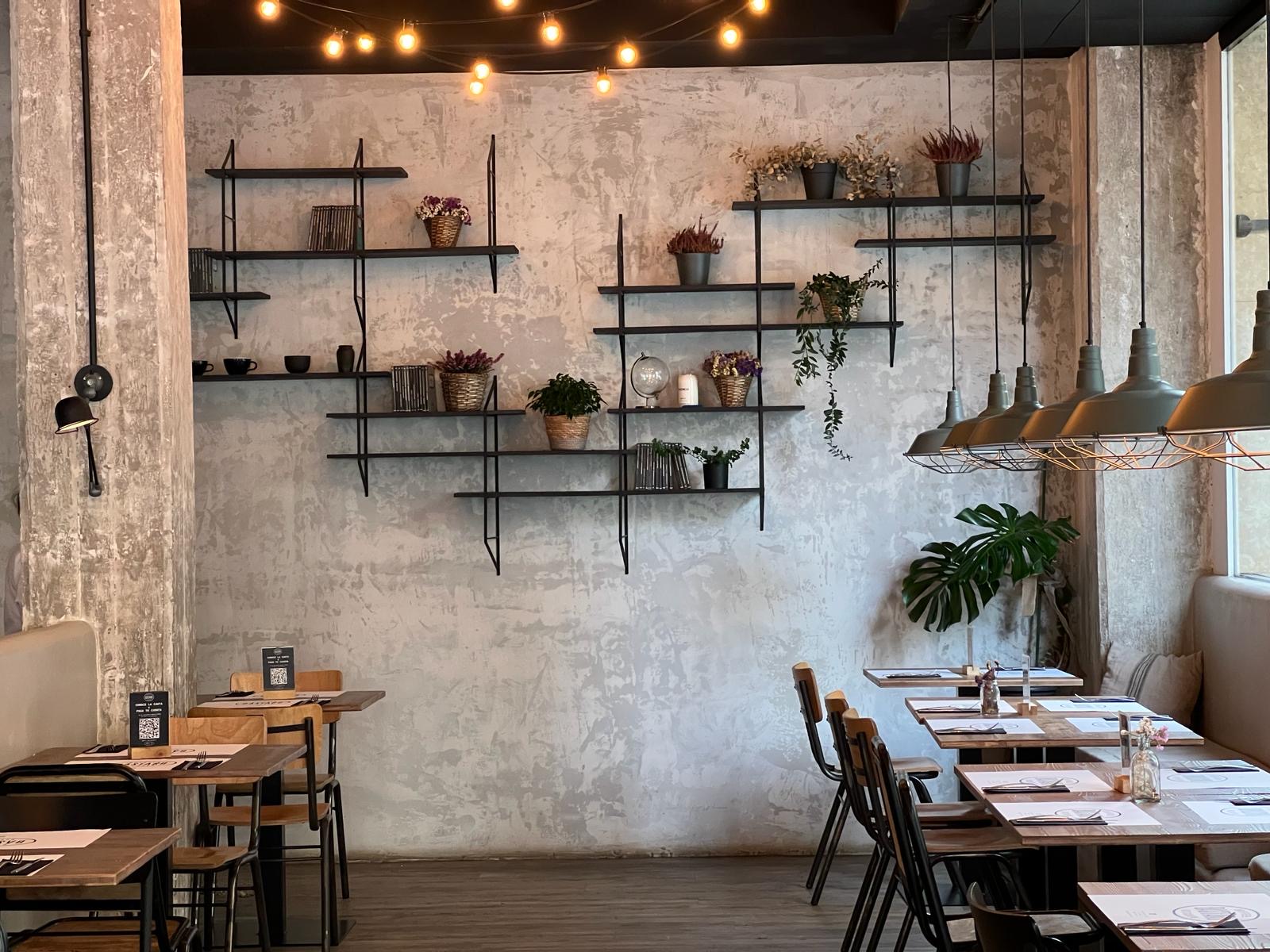 Estilo industrial y acogedor en Bastard Coffee & Kitchen. Luz cálida, detalles verdes y mesas listas para disfrutar sin prisas.
