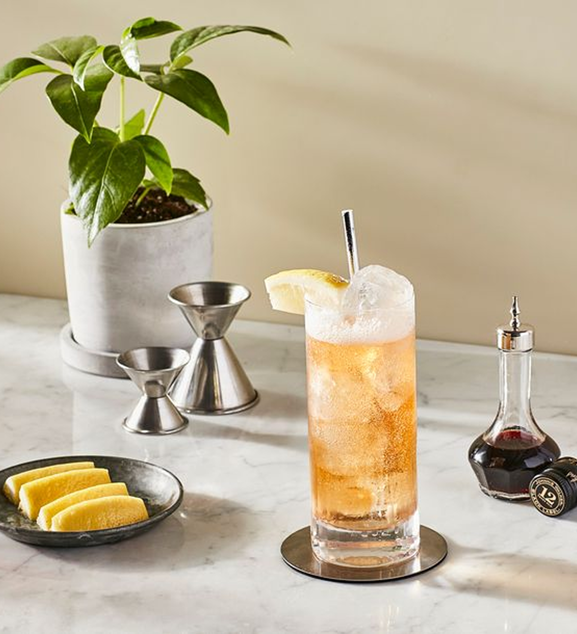 Johnnie Ginger cocktail made with Johnnie Walker Black Label, garnished with lemon on a marble bar setup