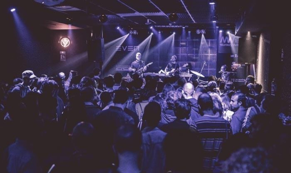 La foto muestra un concierto de música en la Sala Even, con una multitud de personas frente a un escenario donde los músicos están actuando.