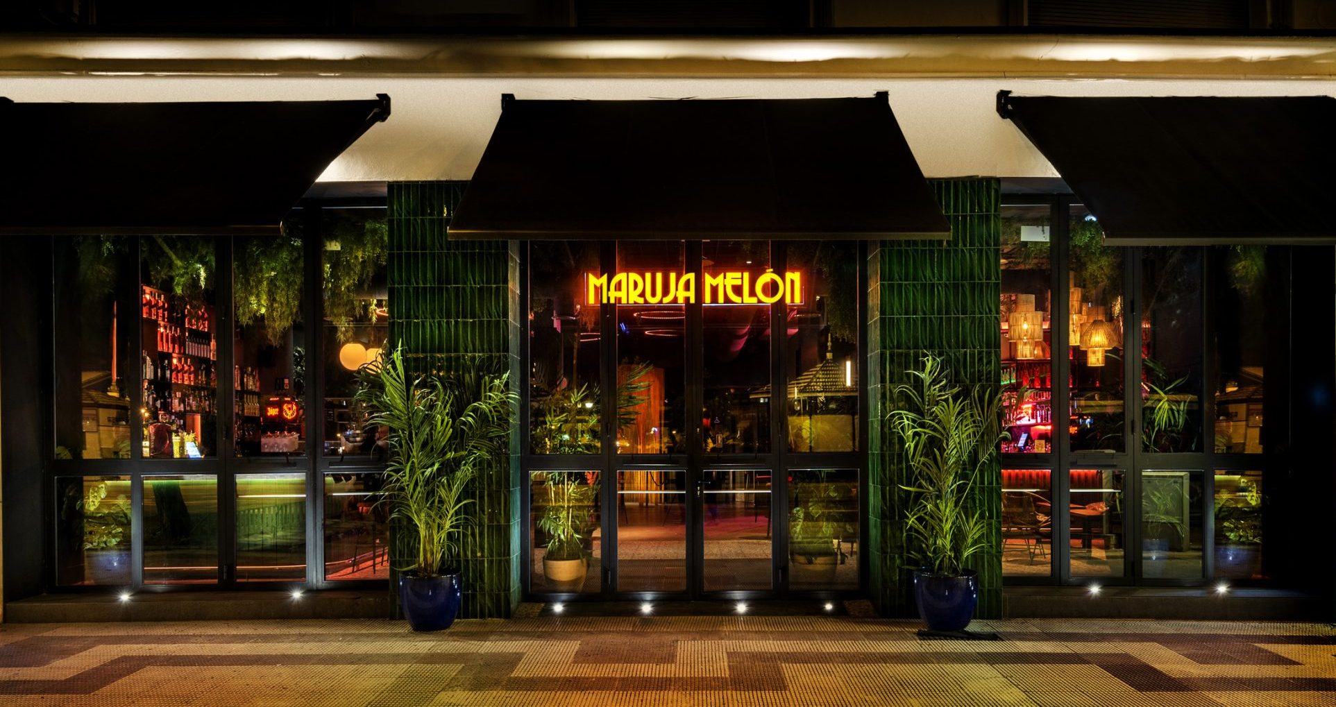 Fachada nocturna de Maruja Melón, con neón vibrante y una atmósfera interior que invita a entrar y dejarse llevar.